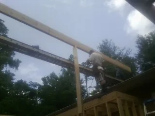 Carpenter setting a ridge beam over a new addition frame — Ice Dam Removal by Roofing Brothers in Perkinston