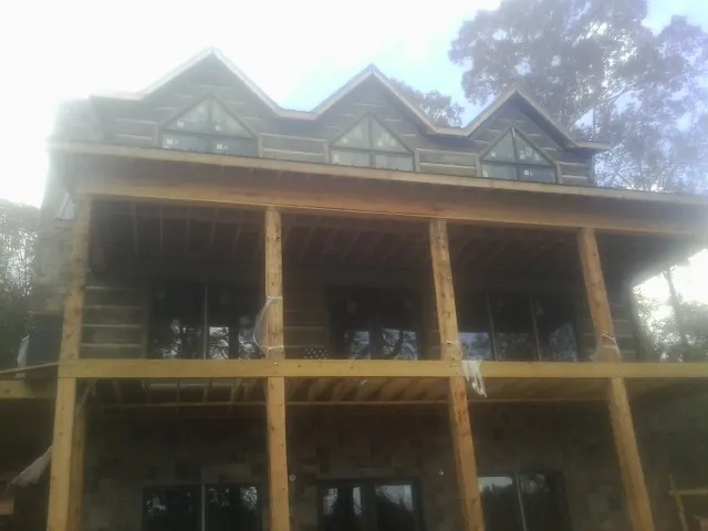 Dormers and porch framing on a large log home under construction — Roof Coating work by our crew in Perkinston