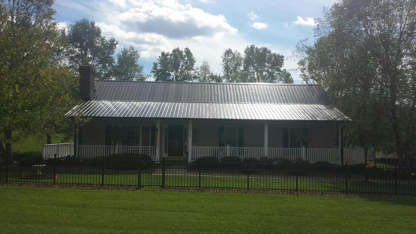 Gray metal roof on a brick ranch with a full width front porch — Gutter Guard Installation work by our crew in Perkinston