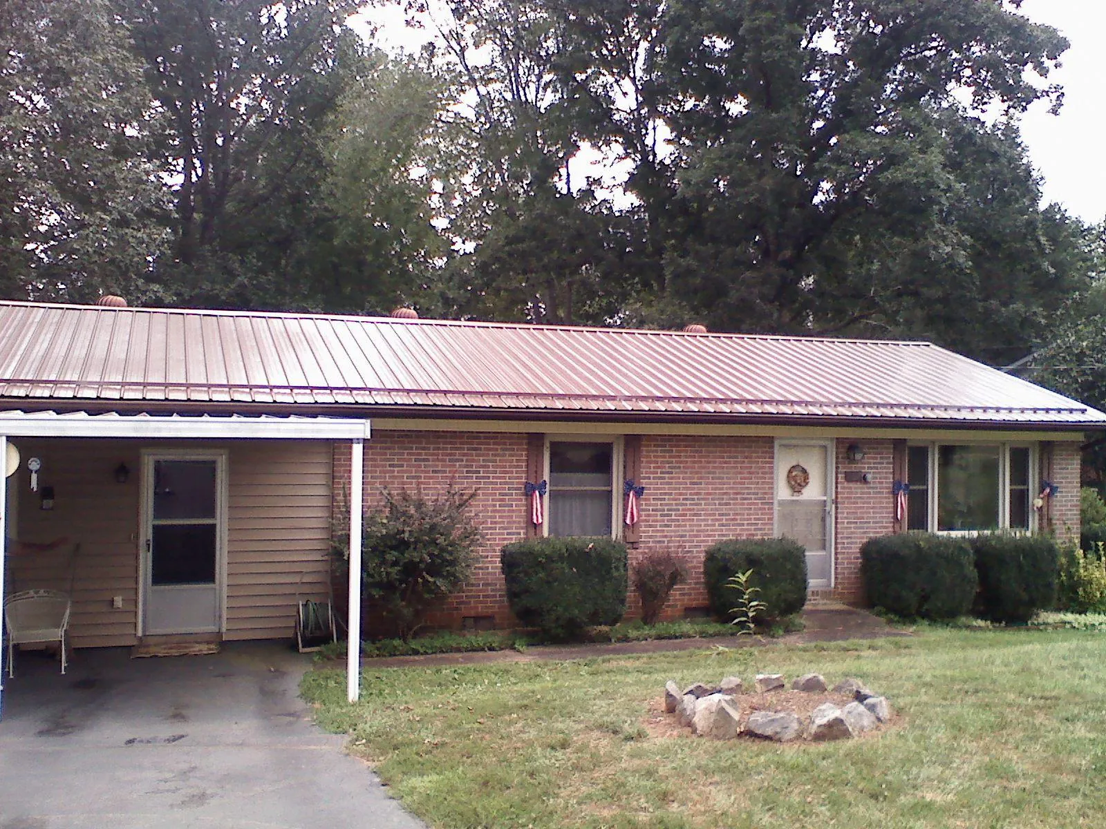 Bronze metal roof and carport on a brick ranch home — Roof Repair work by our crew in Perkinston